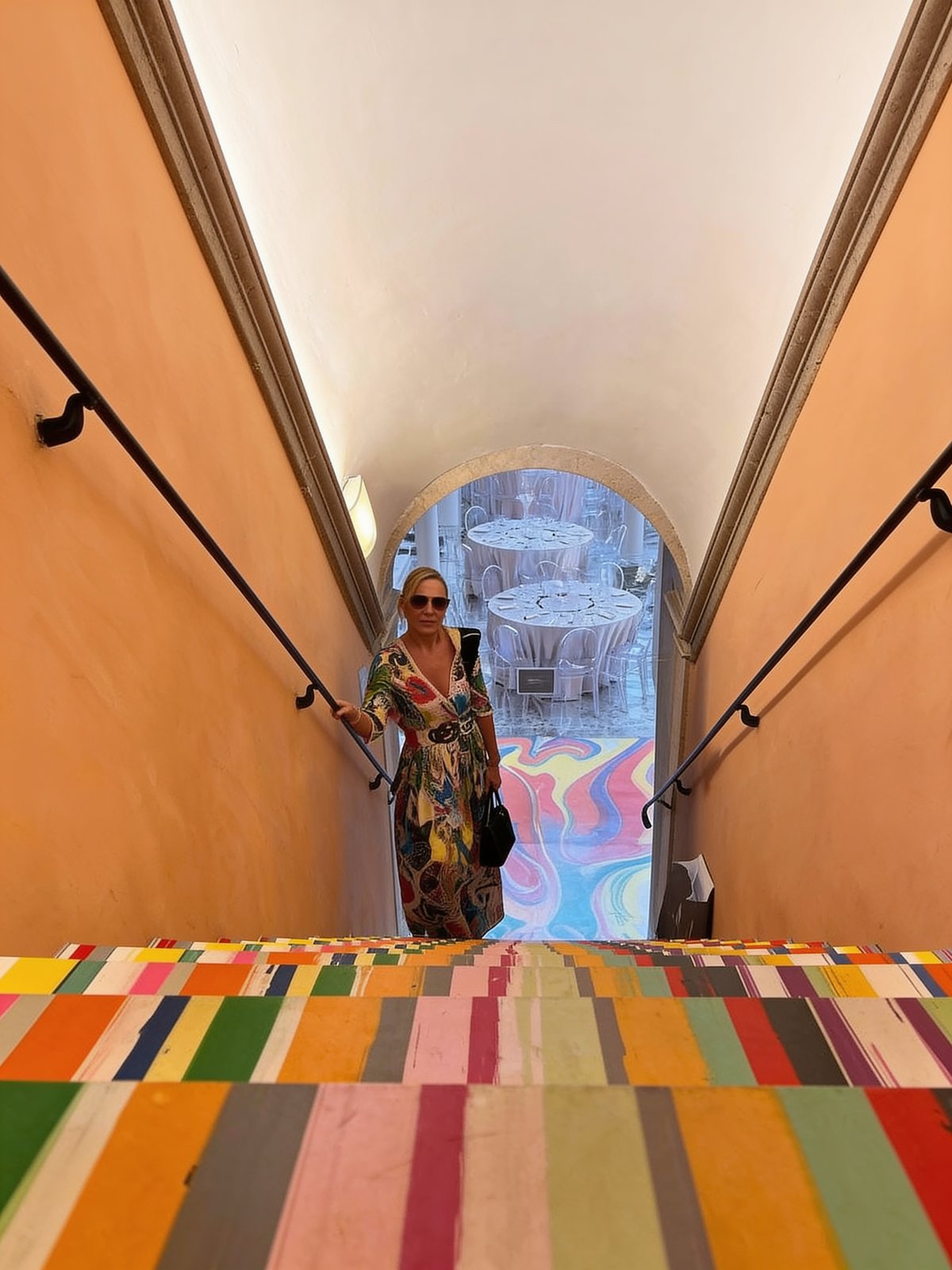 Founder in a colorful print dress on a hand-painted staircase